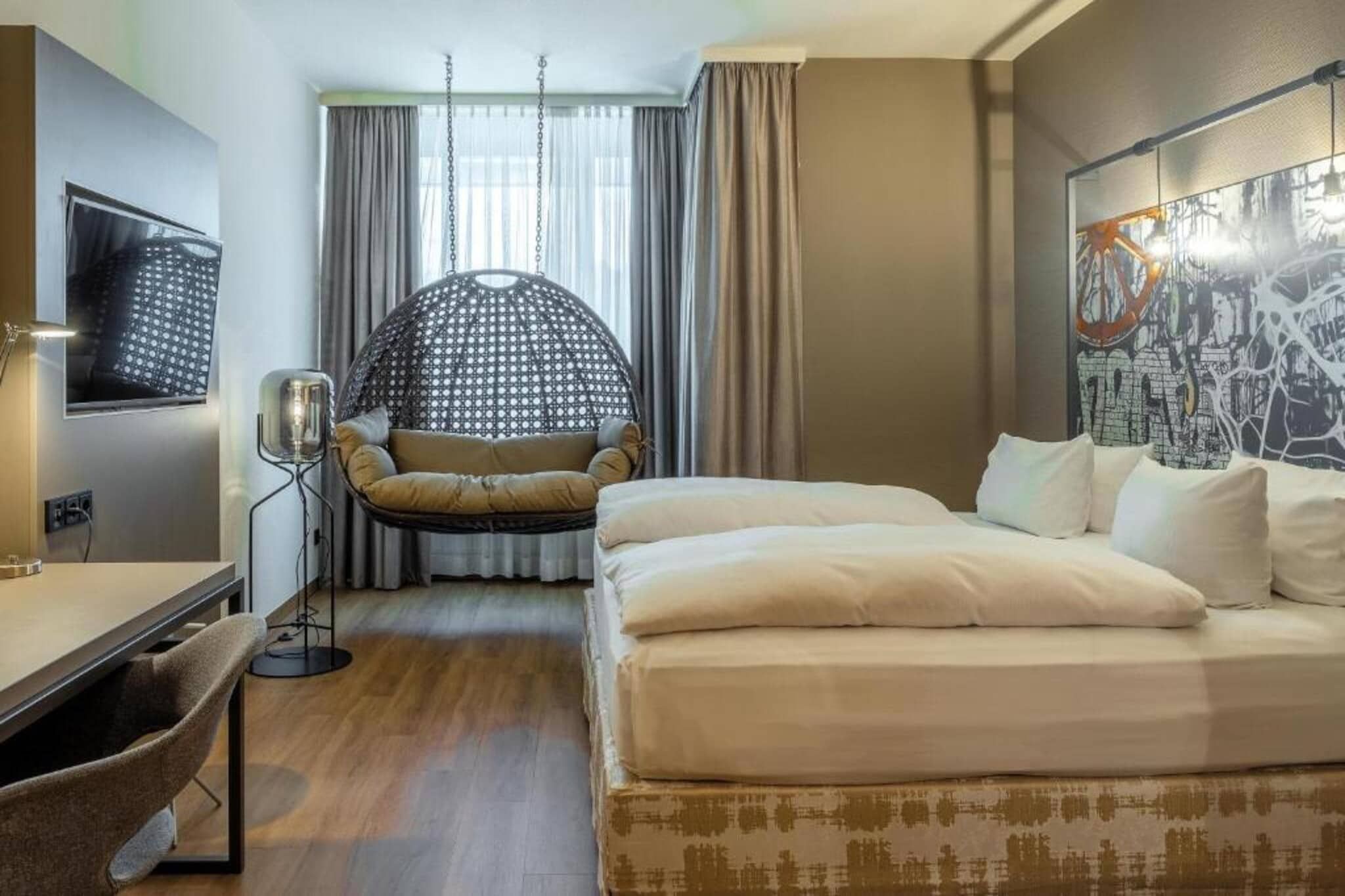 A hotel room with a bed, a chair, a desk, and a TV.