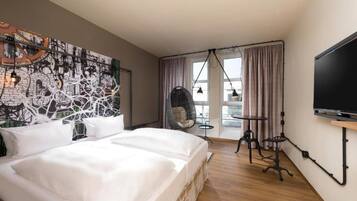 Habitación de hotel con una cama grande, una silla colgante, un televisor y un mural con vistas a la ciudad en la pared.
