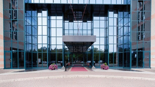 A modern building with a glass facade, a central entrance with a red carpet, and symmetrical design. - Hotel Nürnberg- Superior Plus Room (Nuremberg)