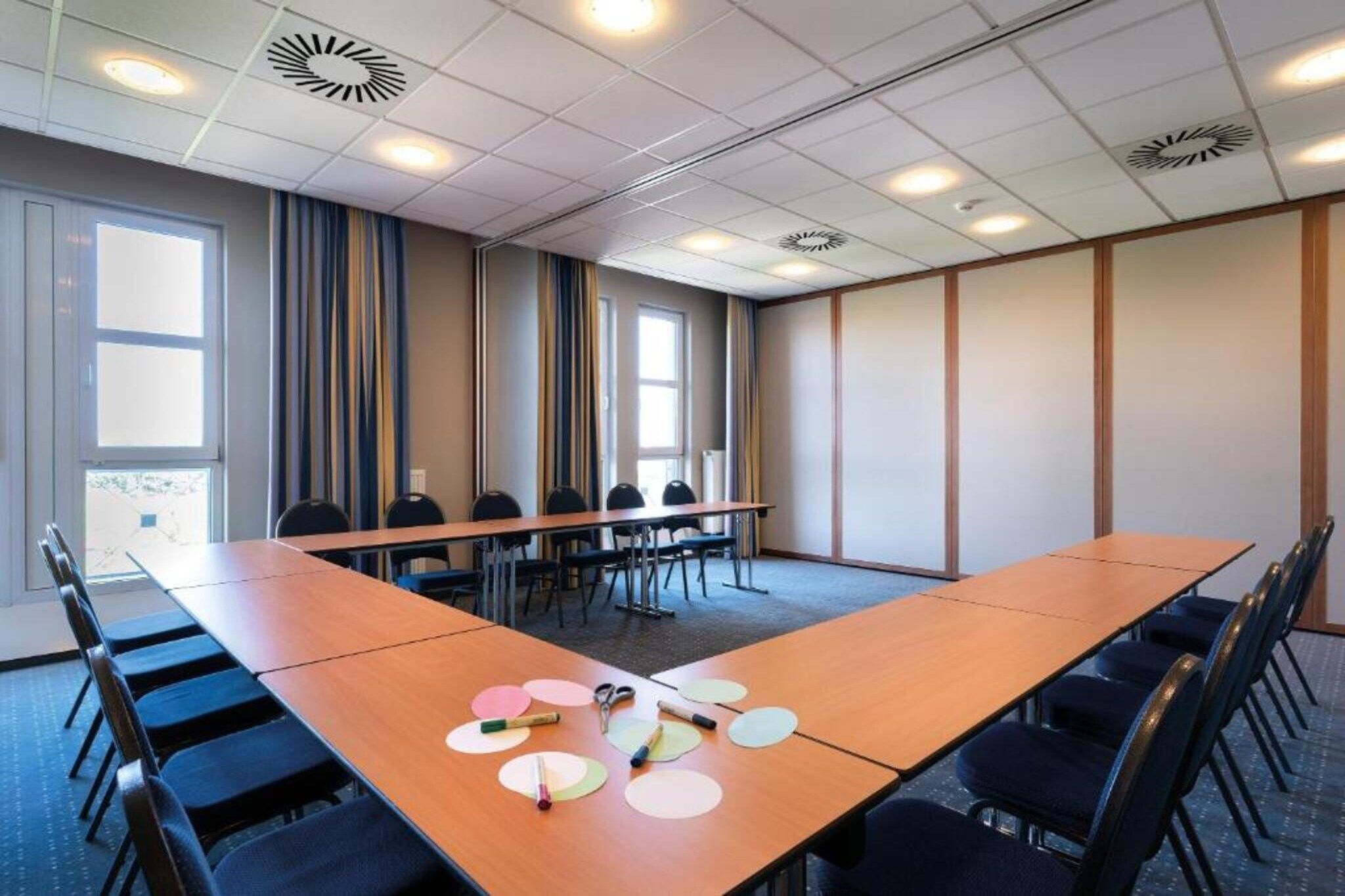 Ein Konferenzraum mit einem langen Tisch, Stühlen und einem Fenster.