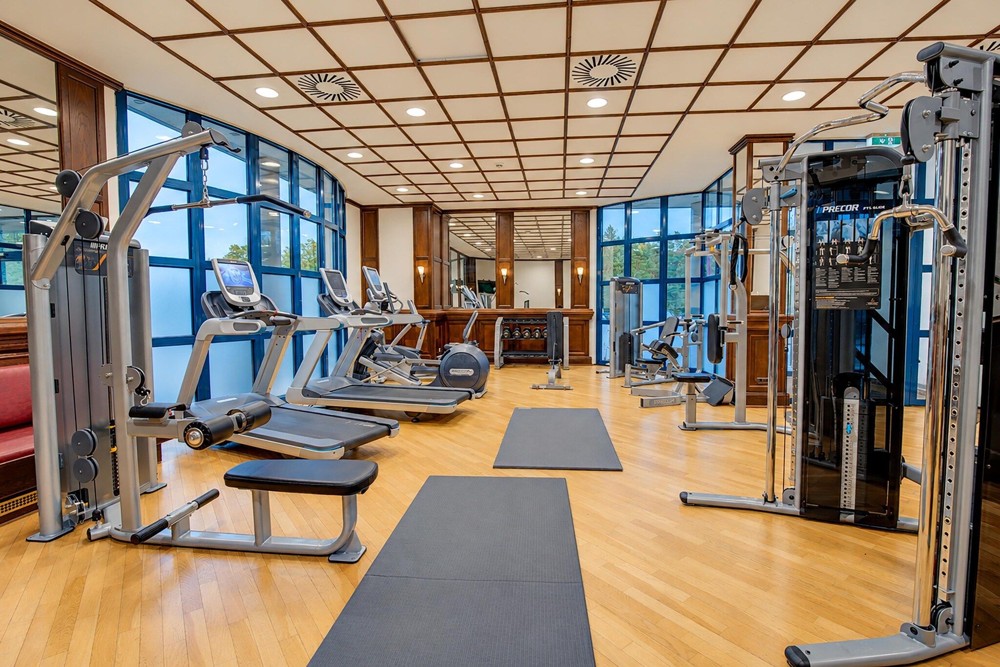A gym with cardio machines, free weights, and a mirrored wall.