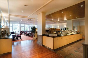 A spacious hotel lobby with a central island, seating area, and large windows. - Hotel Nürnberg- Suite (Nuremberg)