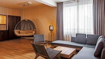 A modern living room with a hanging chair, a sofa, a coffee table, and a floor lamp.