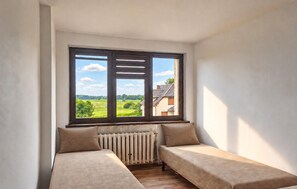 A room with a view of a green landscape through a window.