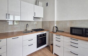 A modern kitchen with white cabinets, a stainless steel sink, a gas stove, an oven, and a microwave.