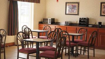 A dining area with multiple tables and chairs, a microwave, and a coffee machine on a counter.