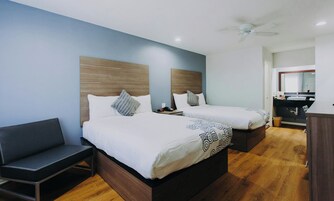 A hotel room with two beds, a desk, and a bathroom.