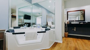 A modern bathroom with a large mirror, a white vanity, and a black sink. - Passport Inn (Kemah)