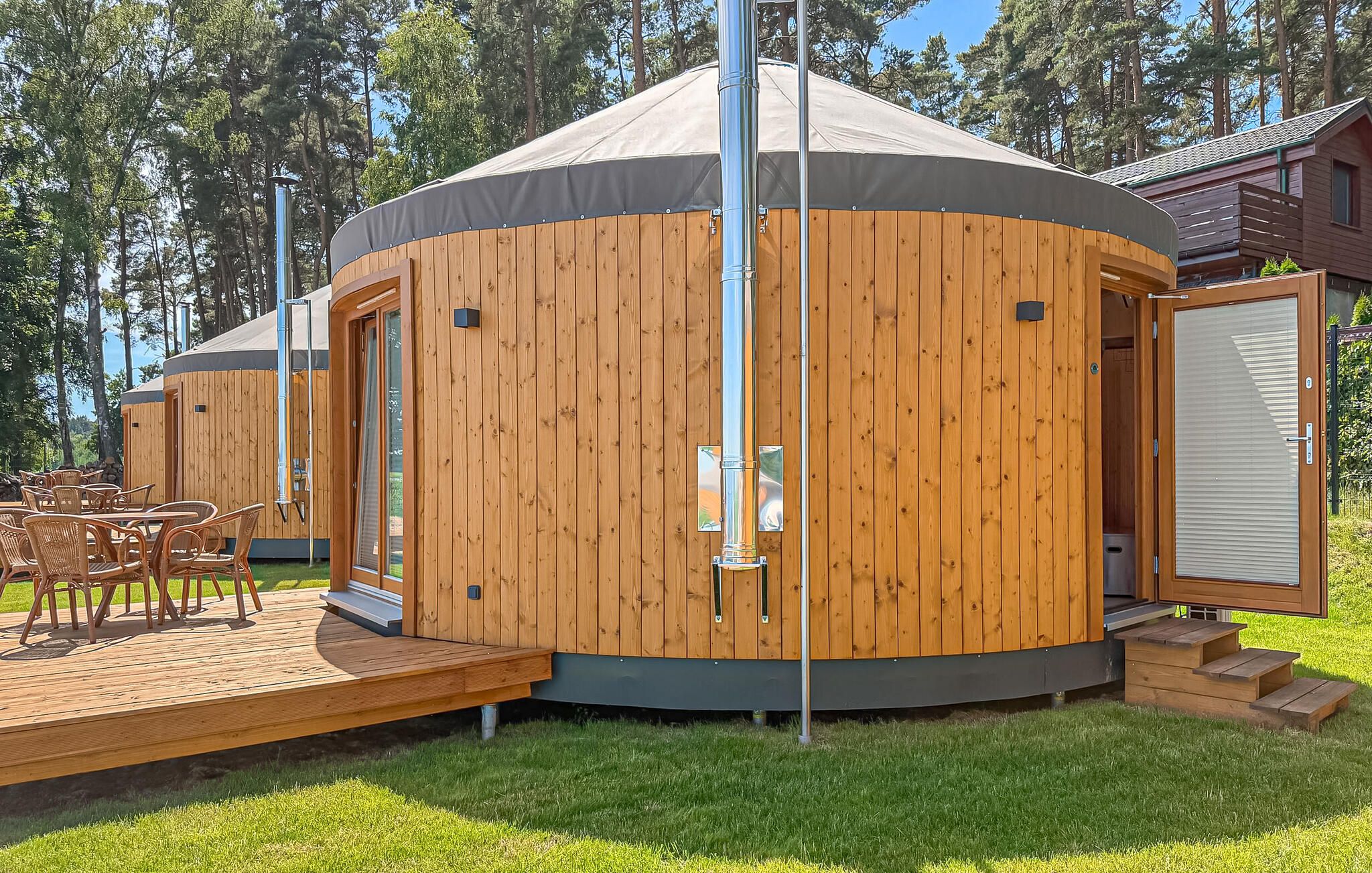 Une yourte en bois dotée d’une terrasse et d’un espace salon extérieur.