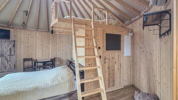 Un intérieur en bois avec un lit superposé, une échelle, un bureau et une chaise.
