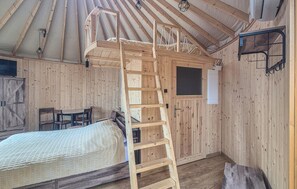 Un intérieur en bois avec un lit superposé, une échelle, un bureau et une chaise.