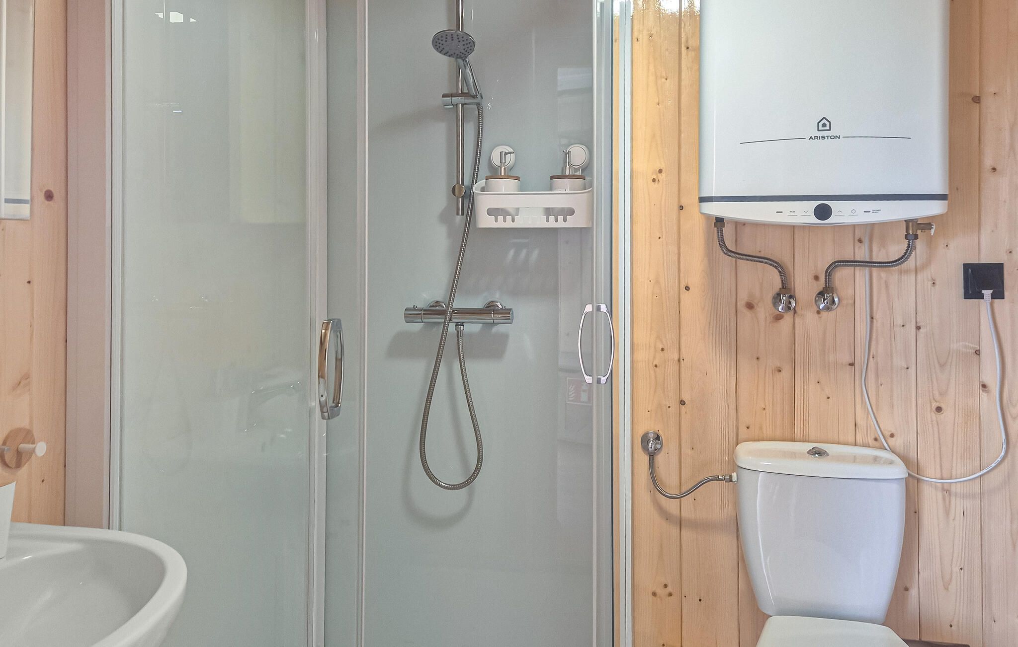 Une salle de bain avec une douche à parois de verre, des toilettes et un lavabo blanc.