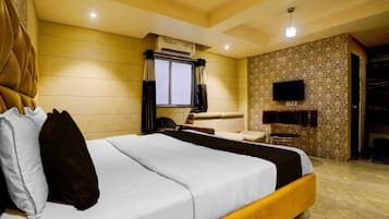 A hotel room with a bed, a television, a window with curtains, and a patterned wall.