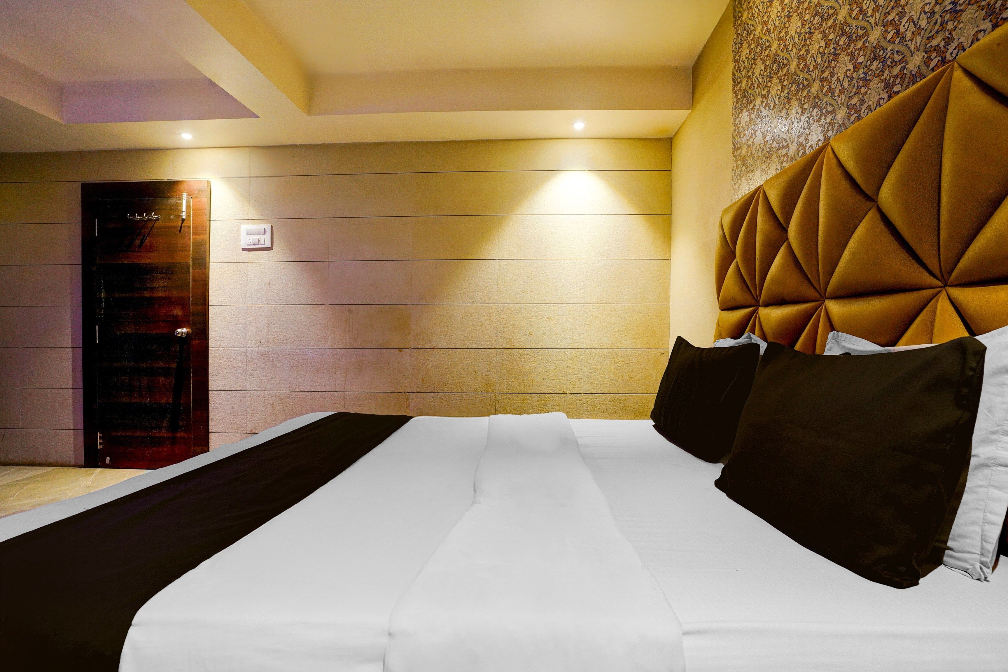 Una habitación de hotel con una cama grande, una puerta de madera y un papel tapiz estampado.