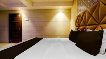 Una habitación de hotel con una cama grande, una puerta de madera y un papel tapiz estampado.