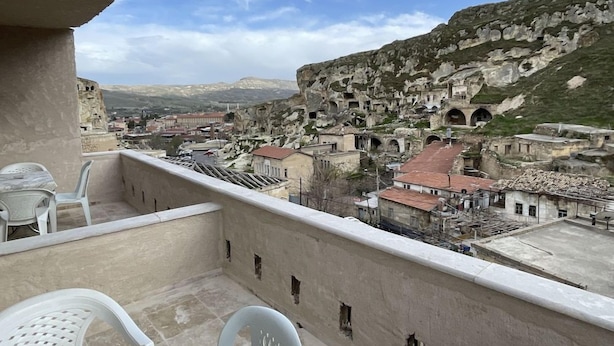 A balcony with a view of a historic town with ruins and a mountainous backdrop. - Dede Hostel Pansiyon (Ürgüp)