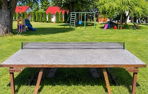 A ping pong table set up outdoors with a playground in the background. - 2 bedroom lovely home in Przewloka (Przewloka)