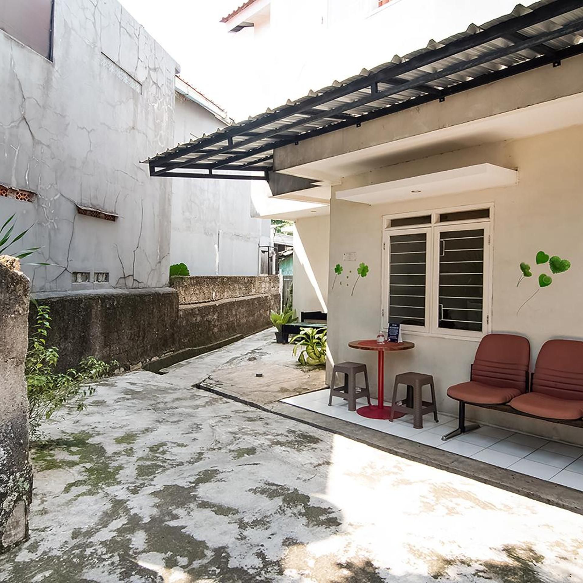 Un patio con zona de estar techada, una mesita y una planta en maceta.