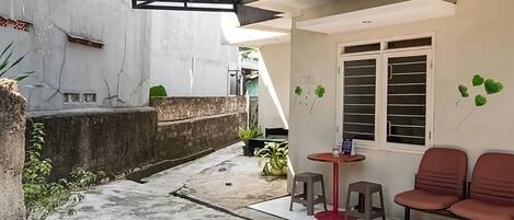 Un patio con zona de estar techada, una mesita y una planta en maceta.