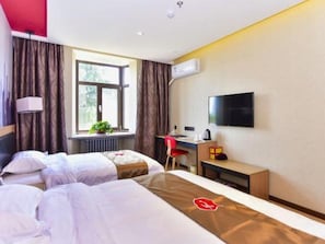 Habitación de hotel con dos camas, un escritorio, una silla, un televisor y una ventana con cortinas.