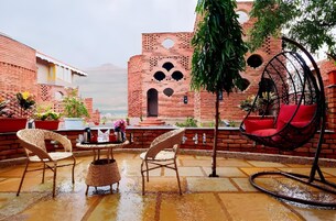 A rooftop terrace with brick walls, a hanging chair, and outdoor furniture.
