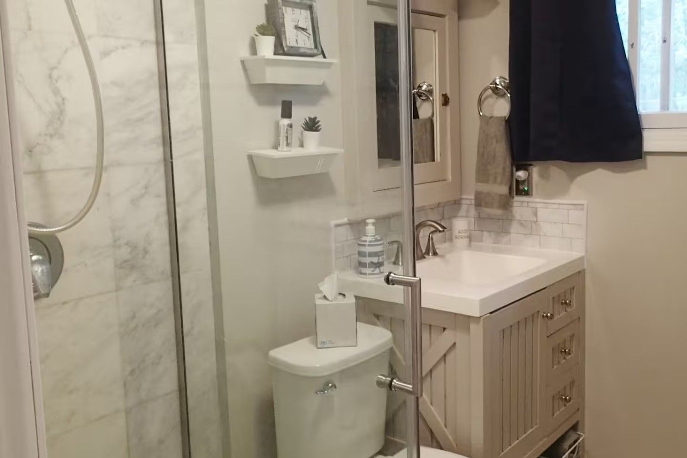 Un baño con cabina de ducha de vidrio, inodoro, lavamanos con espejo y toallero.