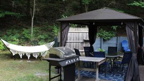 Un pabellón con una parrilla, asientos al aire libre y una hamaca.