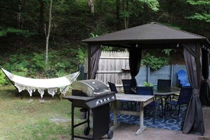Un porxo amb una barbacoa, seients exteriors i una cadira espanyola.