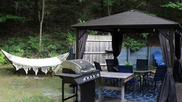 A gazebo with a grill, outdoor seating, and a hammock.
