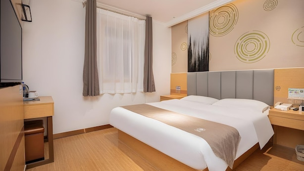 A hotel room with a bed, bedside tables, a desk, a window with curtains, and a wall with abstract art. - Greentree Inn Nanjing Zhongshan Mausoleum Scenic Area Zhongling Street Subway Station (Nanjing)