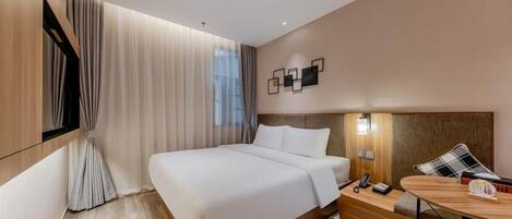Una habitación de hotel moderna con una cama grande, una mesita de noche con lámpara y vistas a la ciudad.