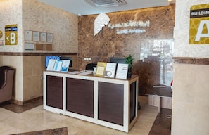 A reception desk with informational displays, a wall-mounted sign, and a plant. - Iwan Alandalusia Hotel Suites Alrehab (Jeddah)