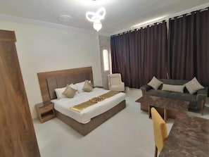 A modern bedroom with a large bed, a sofa, a coffee table, and a nightstand. - Iwan Alandalusia Hotel Suites Alrehab (Jeddah)