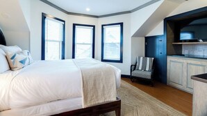 Ein Schlafzimmer mit einem großen Bett, einem Sessel und einer Küchenzeile mit Schränken.