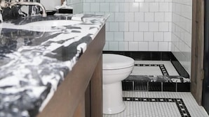 Ein Badezimmer mit Marmorwaschtisch, Toilette, Dusche und Fliesenboden.
