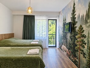 A bedroom with two beds, a large window with curtains, a painting of trees, and a mounted TV. - SKY MORE Hotel & Restaurant Abastumani  (Abastumani)