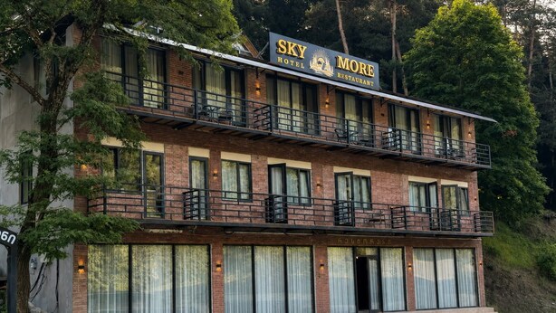 Um edifício de dois andares com uma placa indicando 'Sky Hotel More Restaurant' no nível superior.