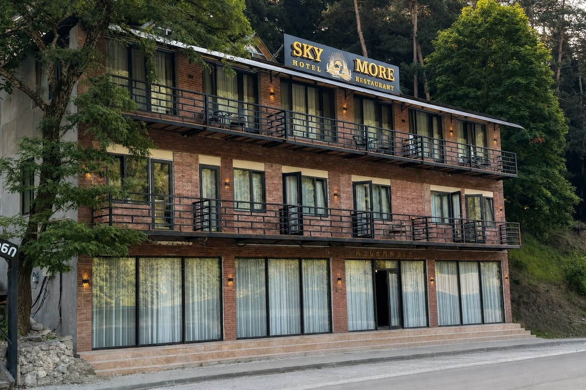 Un edificio de dos pisos con un letrero que dice 'Sky Hotel More Restaurant' en el nivel superior.