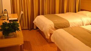 Une chambre d’hôtel avec deux lits, un bureau avec une lampe et une plante en pot.