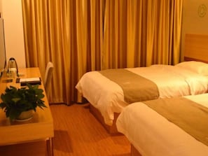 Ein Hotelzimmer mit zwei Betten, einem Schreibtisch mit Lampe und einem Blumentopf.