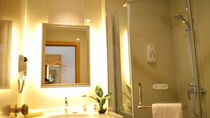 Une salle de bain avec une douche à parois de verre, un lavabo avec un miroir et un porte-serviettes.