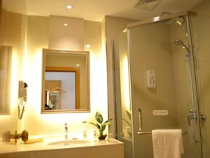Ein Badezimmer mit einer Duschkabine, einem Waschbecken mit Spiegel und einem Handtuchhalter.