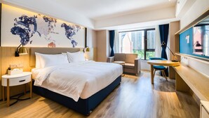 A modern hotel room with a large bed, a desk, a chair, and a world map on the wall. - Kyriad Marvelous Hotel Haerbin West High-speed Railway Station Wanda (Harbin)