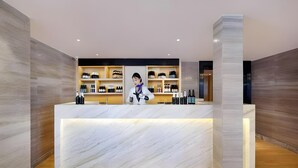 A reception desk with a marble top, wooden flooring, and shelves with various items. - Kyriad Marvelous Hotel Haerbin West High-speed Railway Station Wanda (Harbin)