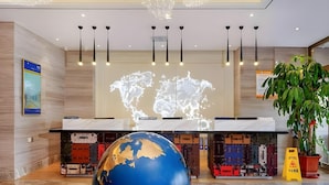 A lobby with a large globe, a world map projection, and luggage storage. - Kyriad Marvelous Hotel Haerbin West High-speed Railway Station Wanda (Harbin)