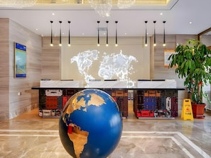 A lobby with a large globe, a world map projection, and luggage storage. - Kyriad Marvelous Hotel Haerbin West High-speed Railway Station Wanda (Harbin)