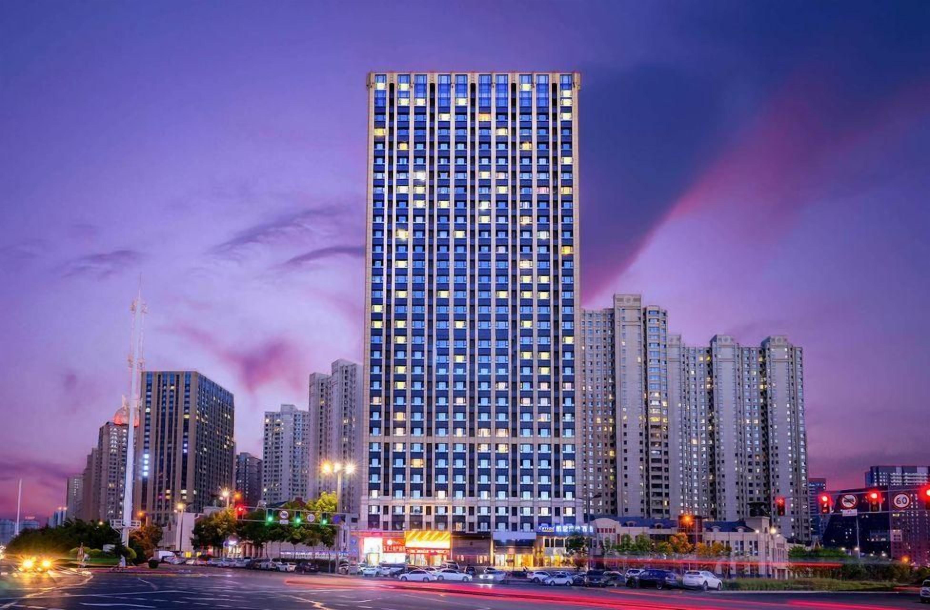 A high-rise building with multiple floors, surrounded by other tall buildings, and a busy intersection with traffic lights.