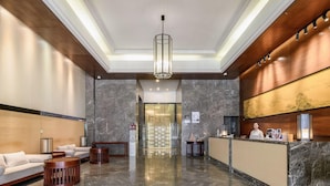 En hotellobby med en receptionsdisk, en sittgrupp och en modern kristallkrona.
