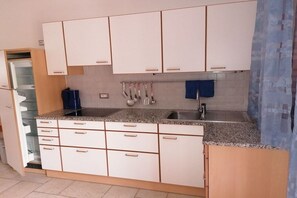 Eine Küche mit weißen Schränken, einer Granit Arbeitsplatte und einem eingebauten Backofen.