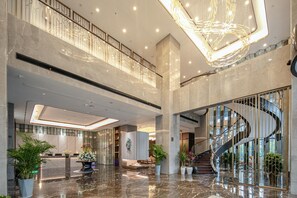 Eine geräumige Lobby mit Marmorboden, einer Rezeption und einer modernen Treppe.